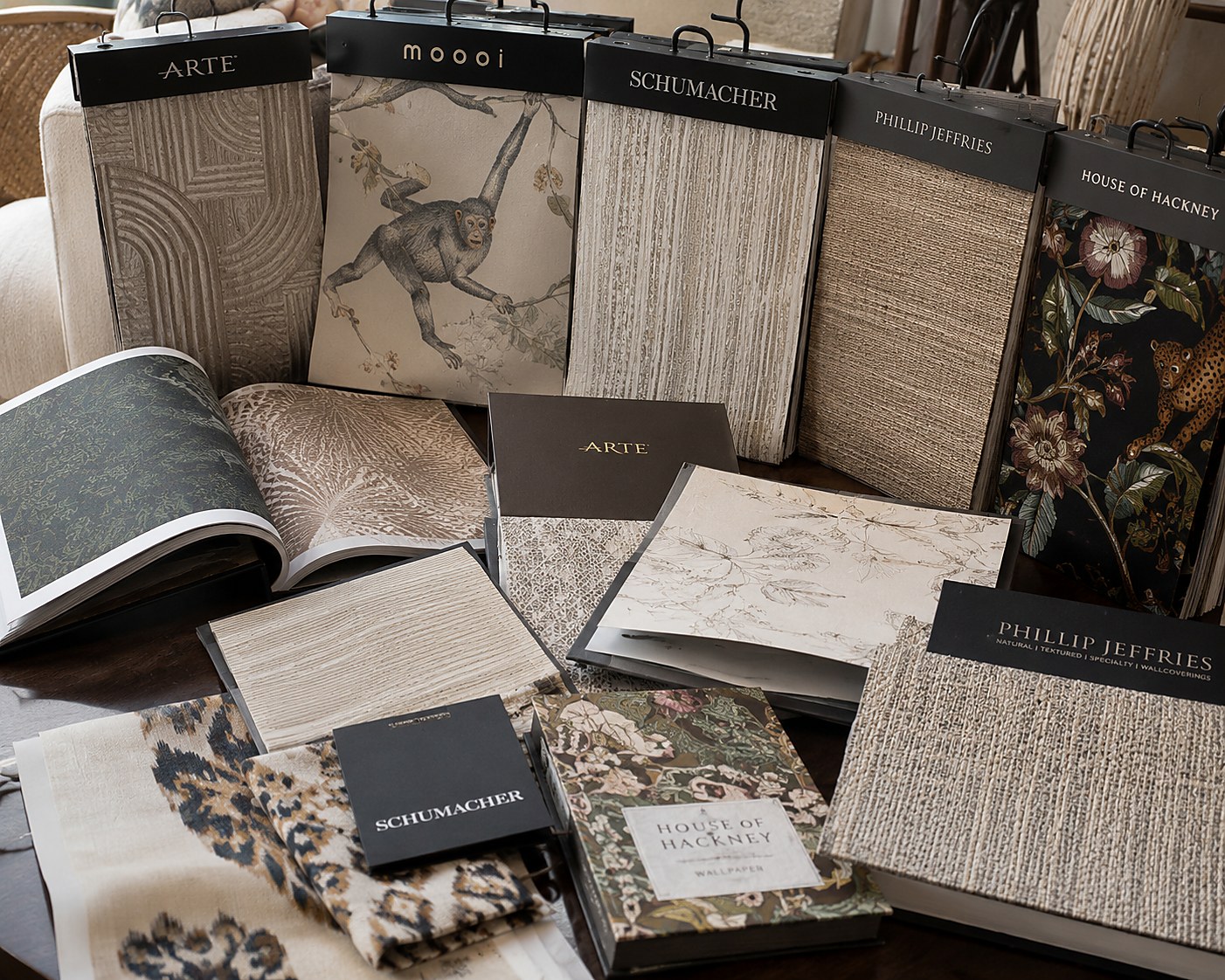 A curated library of designer wallpaper sample books, including Schumacher, Phillip Jeffries, House of Hackney, and Arte