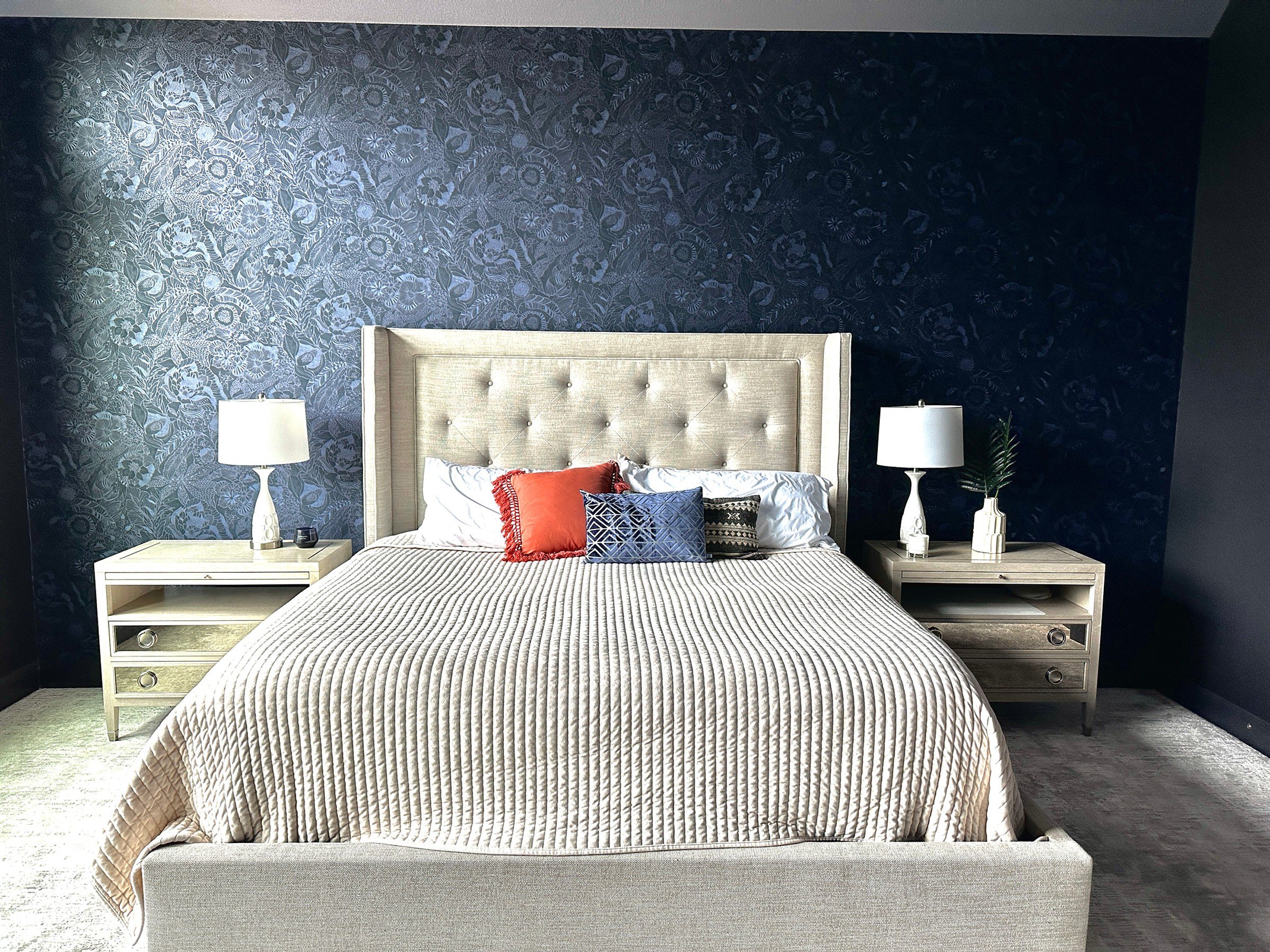 Navy floral wallcovering behind a tufted headboard in a bedroom, a Style Maison installation