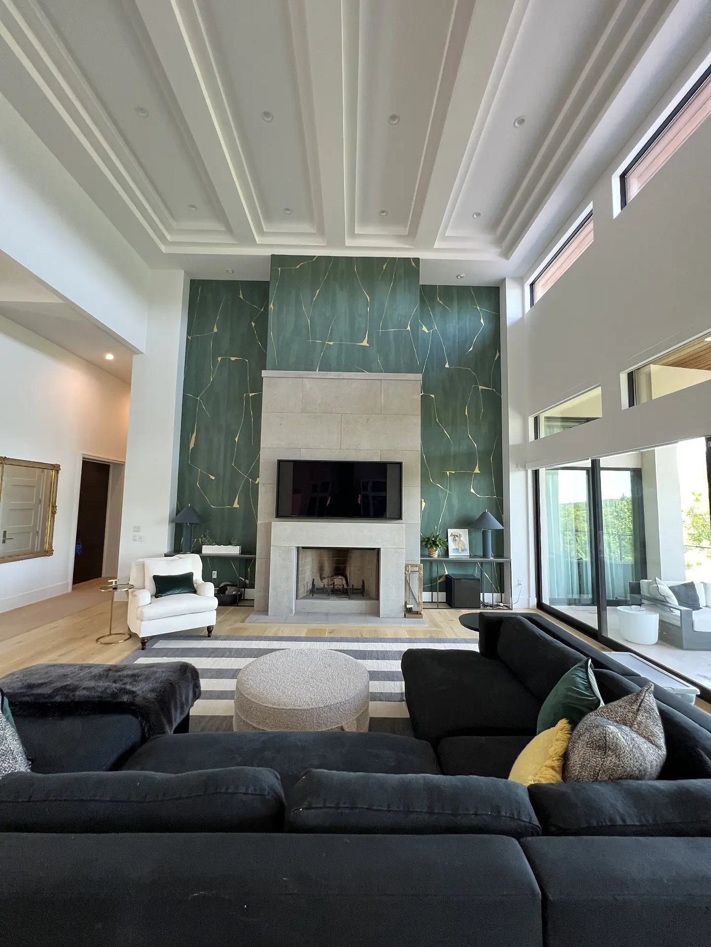Living room with a green and gold wallcovering above the fireplace, installed by The Style Maison
