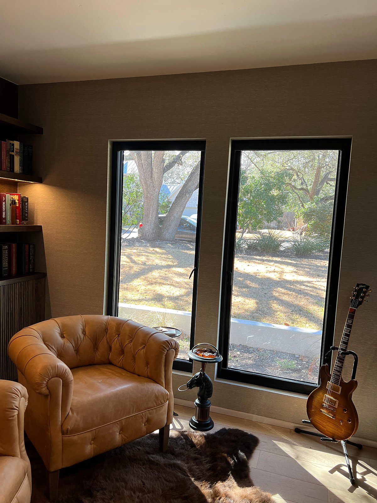 Grasscloth-covered study with a leather armchair and guitar, a real Style Maison project