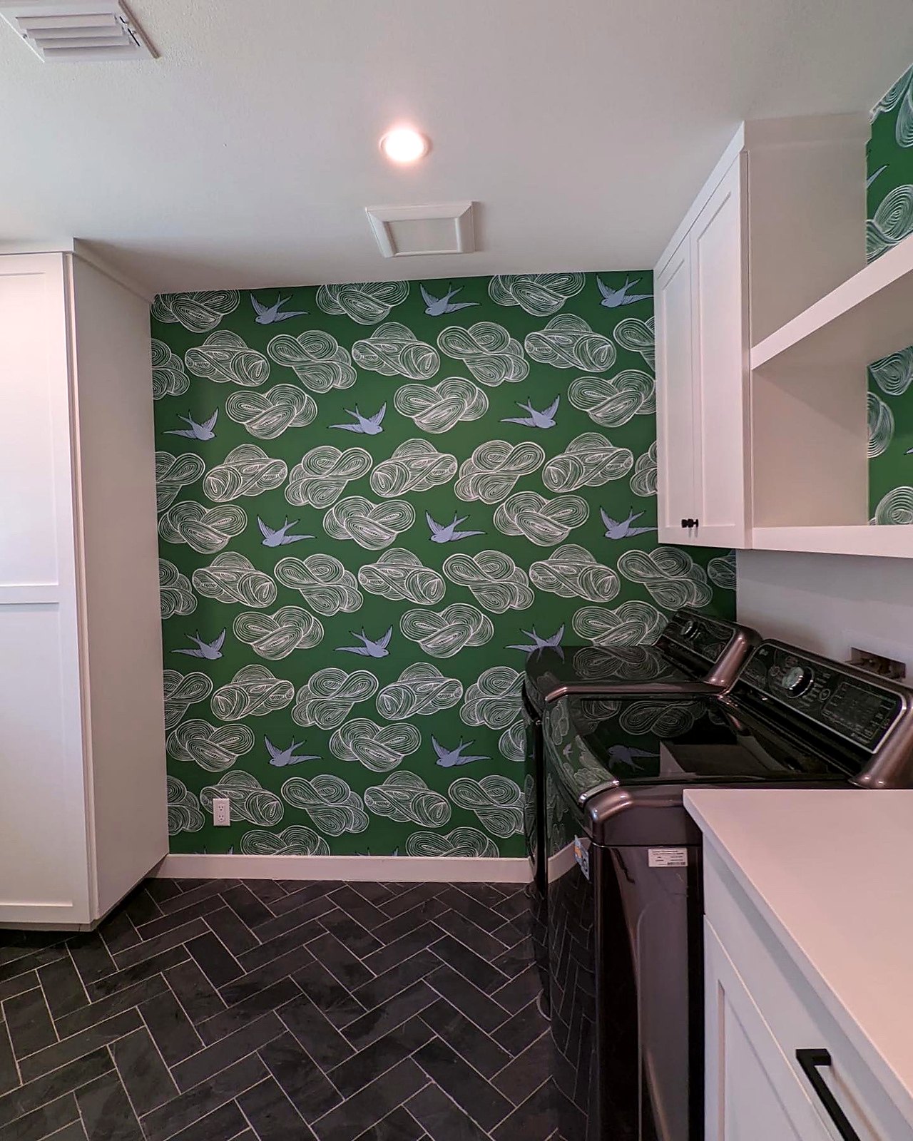 Leaf-print wallpaper accent wall in a laundry room
