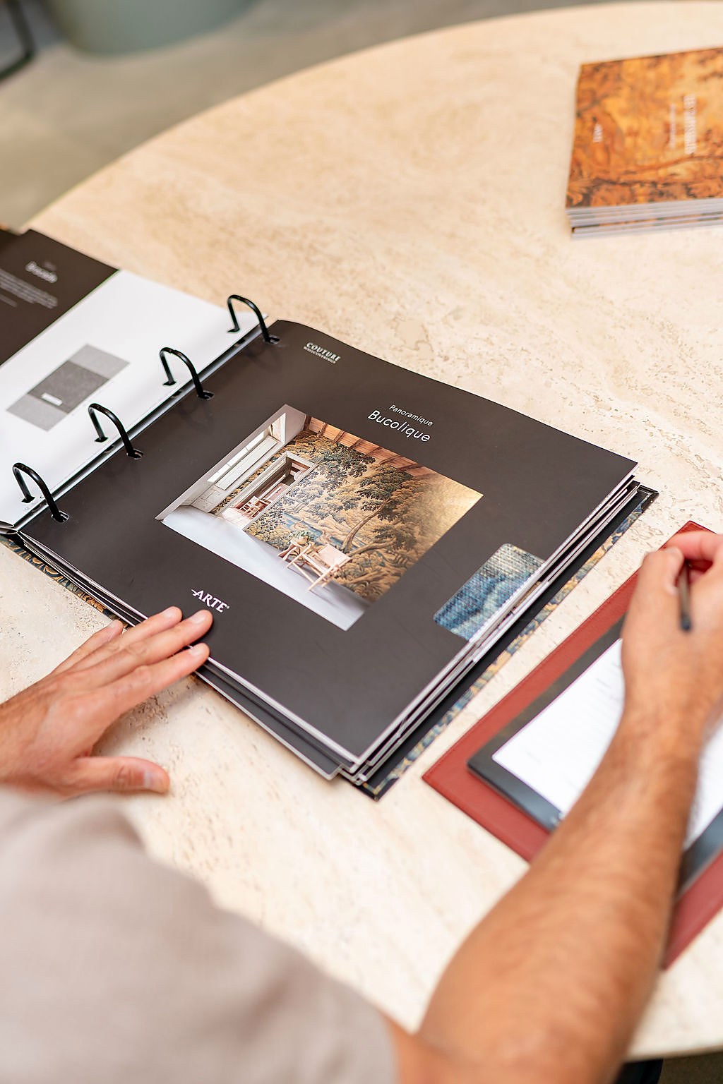 Flipping through a wallcovering sample binder on a marble table
