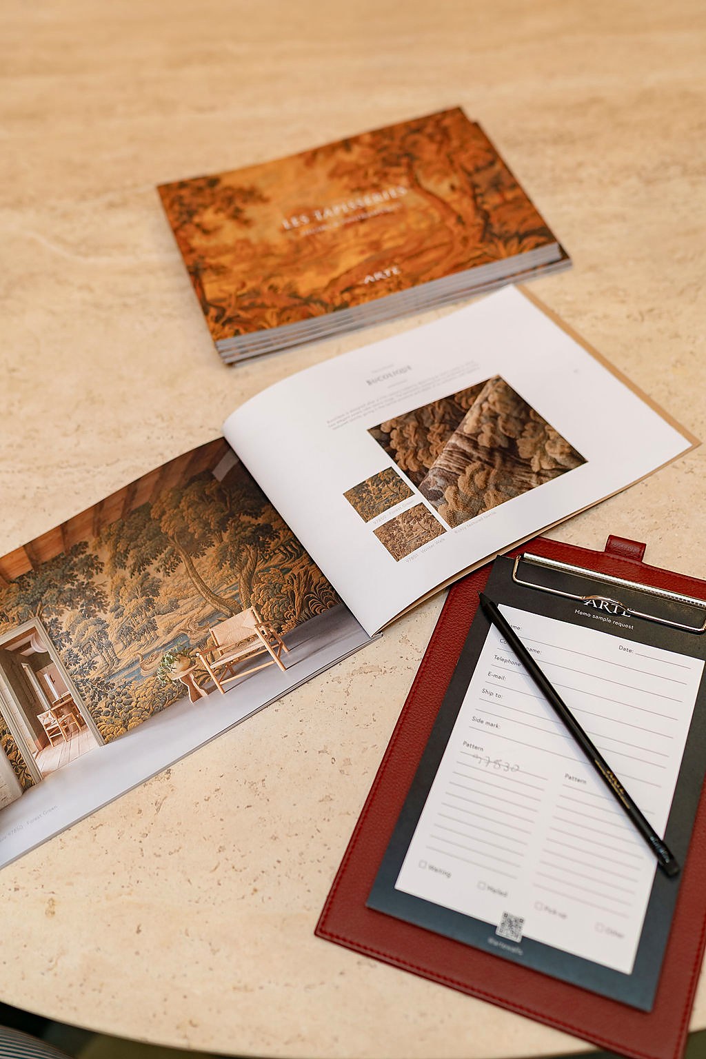 Designer wallcovering sample books and an order pad on a marble table